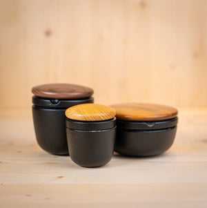 schwedischer gusseisen mörser mit Holzdeckeln in verschiedenen Größen auf Holzuntergrund