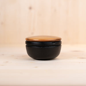 schwedischer gusseisen mörser mit Holzdeckel auf hellem Holzuntergrund