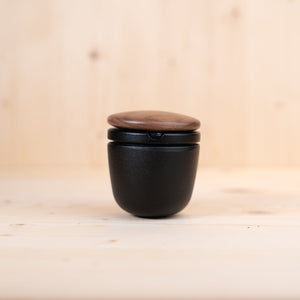 Schwedischer gusseisen mörser in elegantem Design mit Holzdeckel, ideal für Gewürze und Pfeffer.