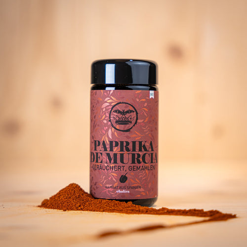 Geräucherte Paprika aus Murcia BIO in einer schwarzen Dose mit Paprika-Pulver auf Holzuntergrund.