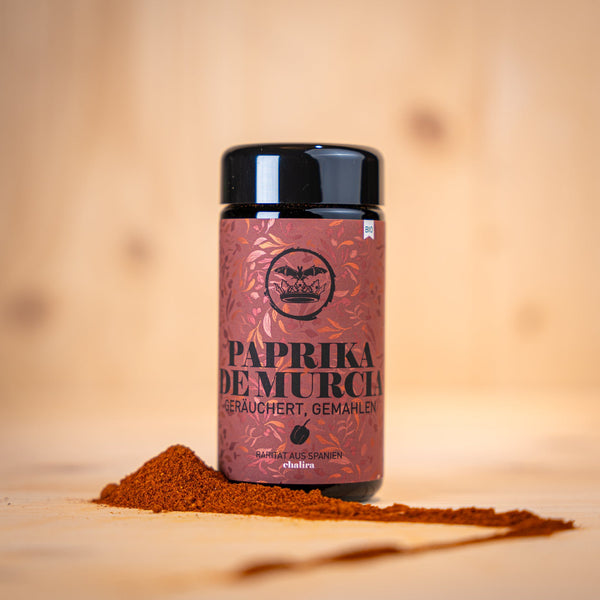 Geräucherte Paprika aus Murcia BIO in einer schwarzen Dose mit Paprika-Pulver auf Holzuntergrund.