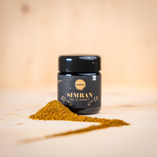 SIMRAN - Ras el hanout BIO Gewürz mit aromatischem Geschmack und goldener Farbe auf Holzuntergrund.