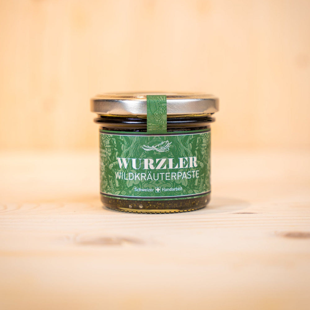 WURZLER Wildkräuterpaste Rezept im Glas mit Löffel, präsentiert auf natürlichem Holzuntergrund.